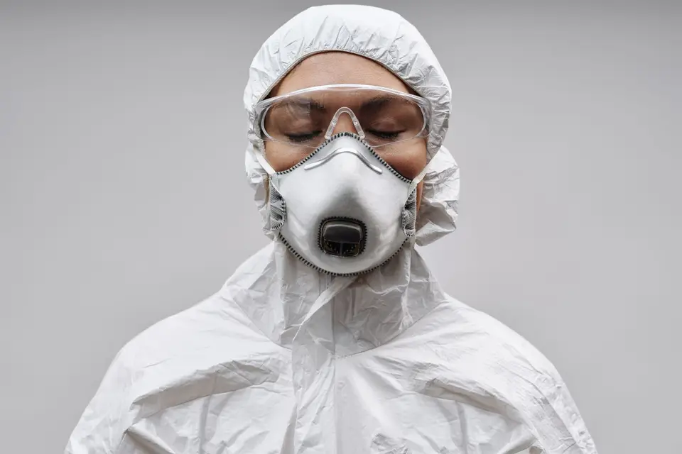 Intervenant en combinaison blanche à capuche, avec lunettes et masque respiratoire